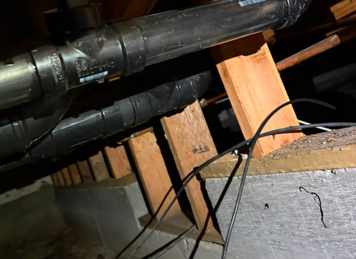 Cast iron and ABS drain lines running through a crawlspace